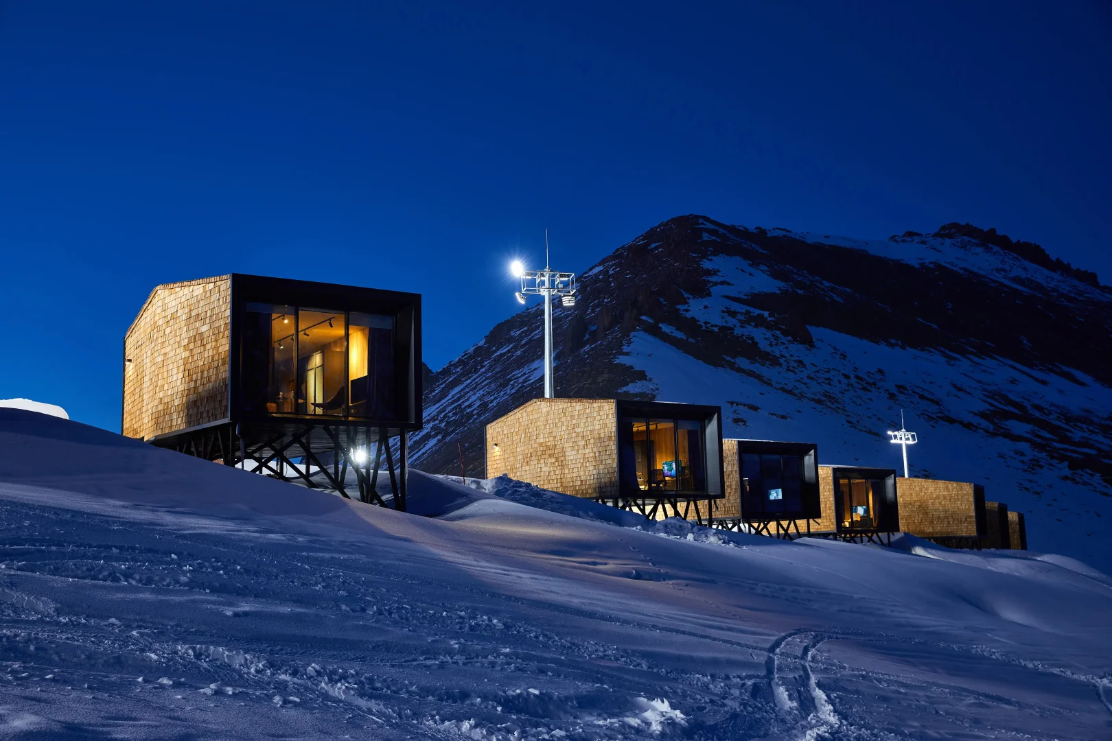 Модули Tenir Eco Hotel на опорах на заснеженном склоне ночью